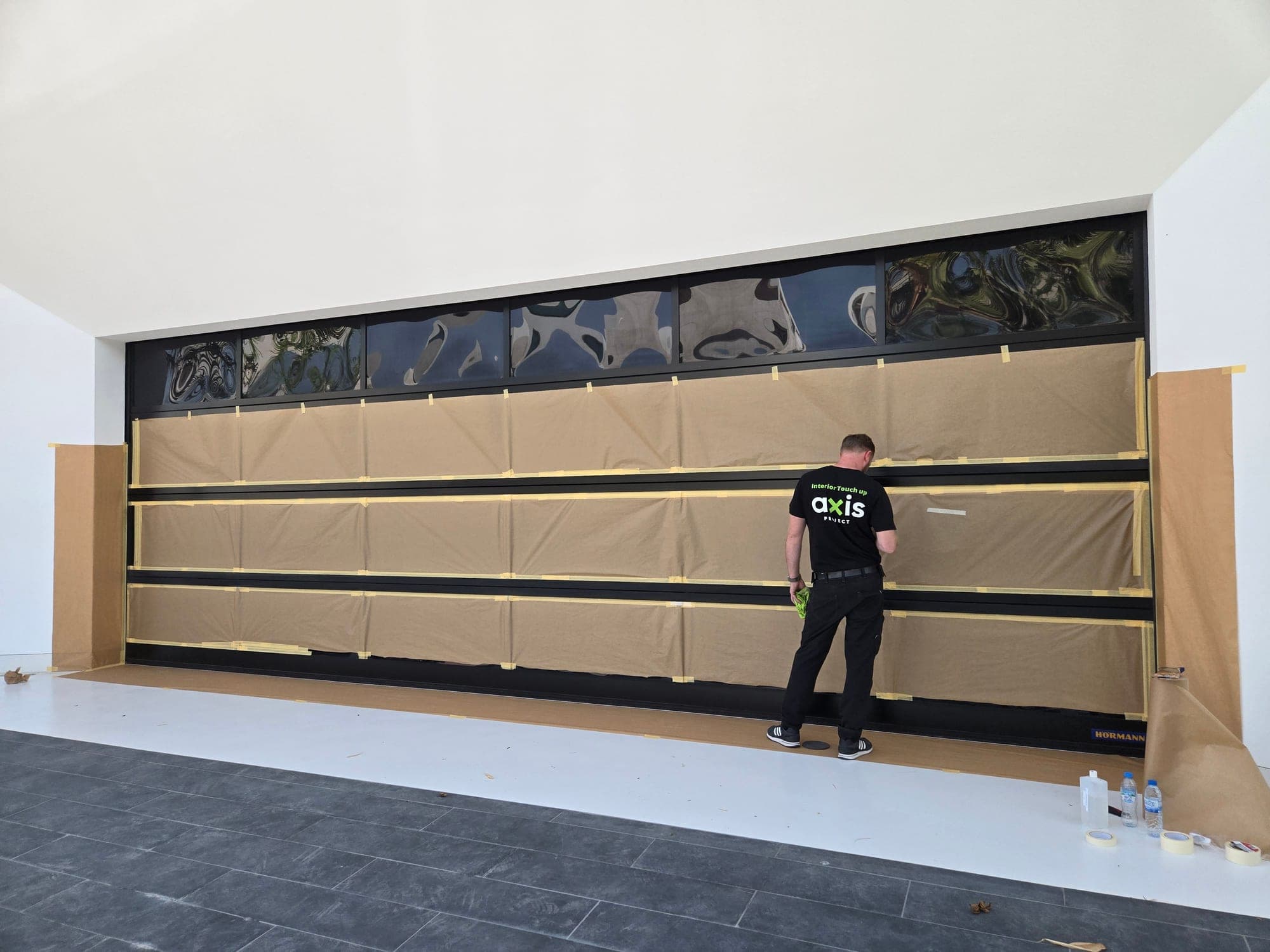 Large black aluminium glazed door masked for on-site refinishing